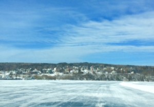 Frozen Ice road with distant view of winter scene small town, wispy clouds.