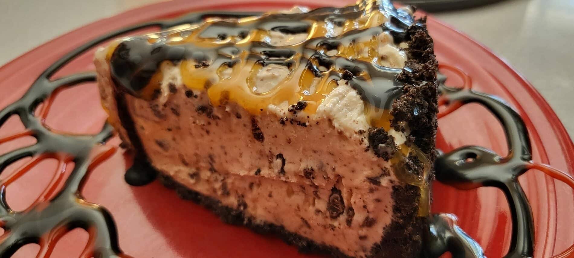 slice of chocolate chip and toffee ice cream pie in an Oreo cookie crust drizzled with caramel and chocolate sauce on a red plate
