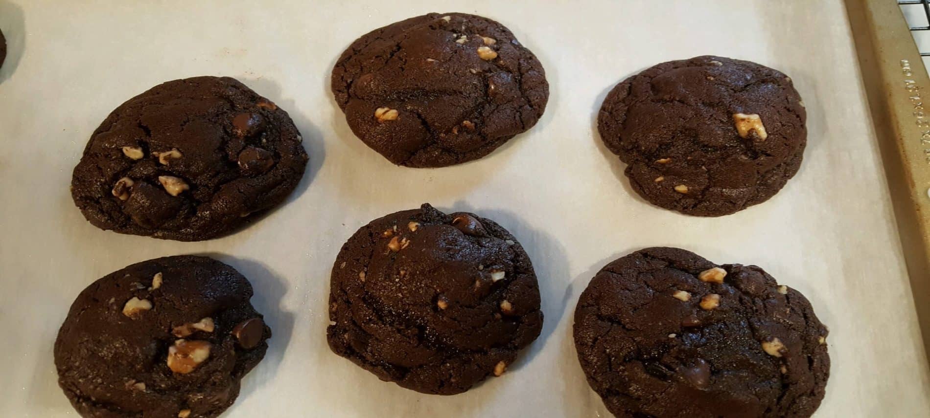 six chocolate chunky cookies on white parchment paper on cookie sheet