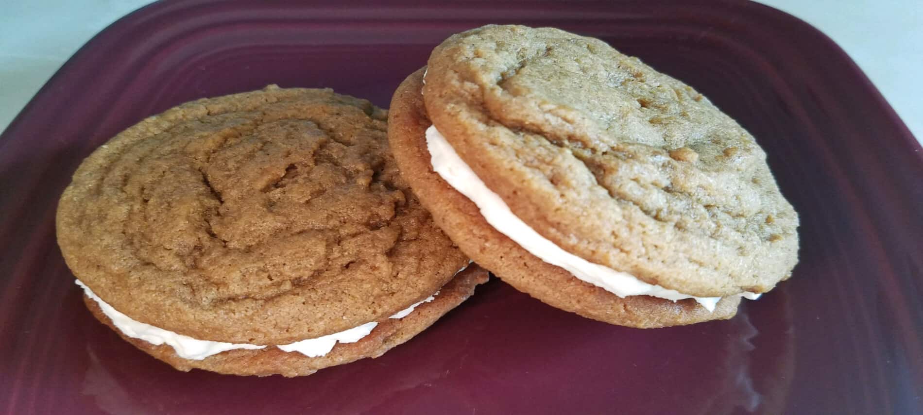 ginger molasses sandwich cookies with cream filling on burgundy plate