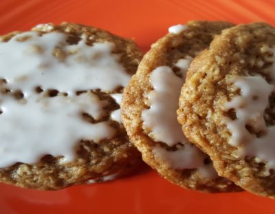 stack of white iced oatmeal cookies on orange plate