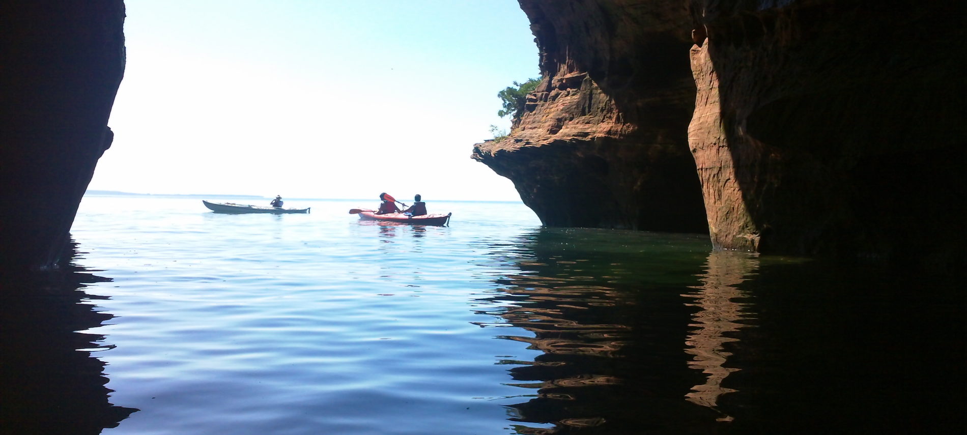 kayakers on Lake Superior next to brownstone formations of the Apostle Islands