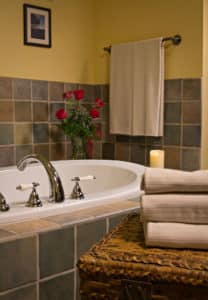 White jetted tub surrounded by tile and topped with fresh red roses