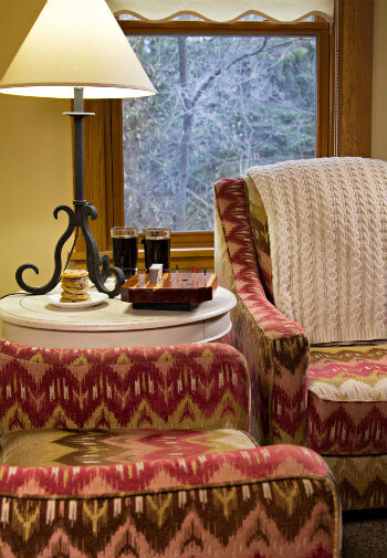 Colorful southwestern styled upholstered chairs flanking a white round table with lamp, cookies, and drinks