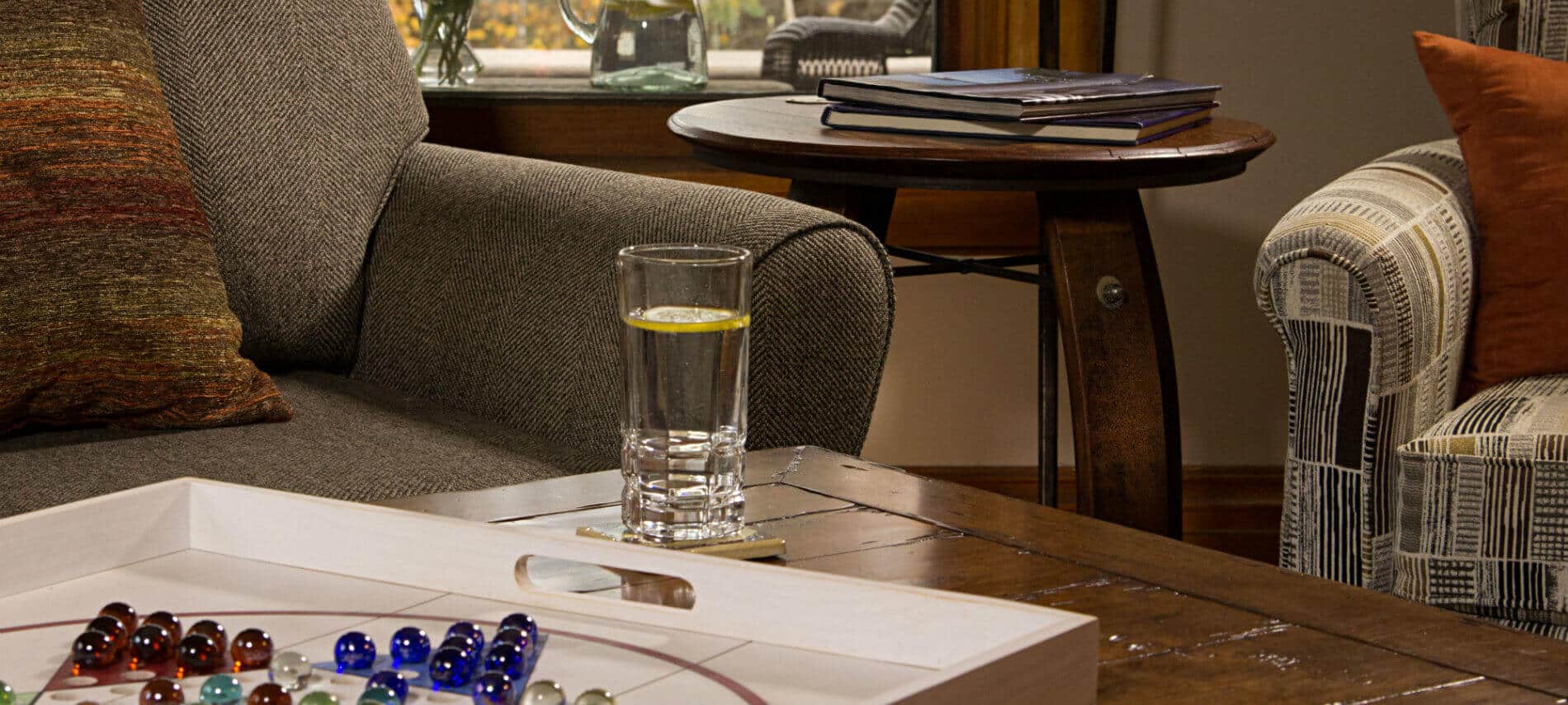 Wood coffee table topped with Chinese checkers game and a glimpse of an upholstered sofa, chair and round table