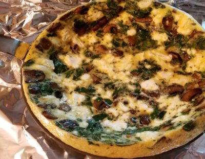 spinach mushroom goat cheese frittata in silver skillet on foil lined cookie sheet